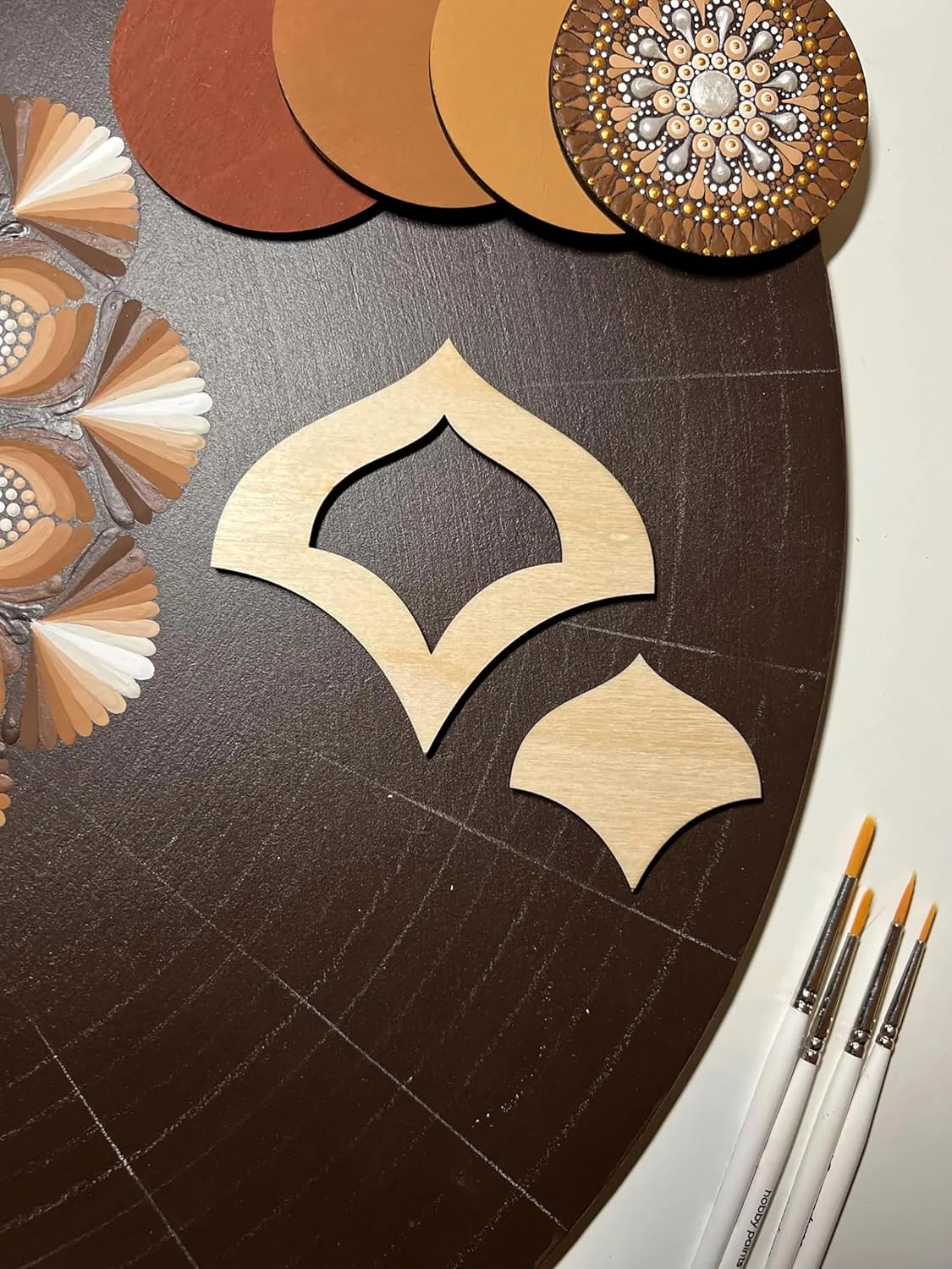 Decorative wooden cutouts on a dark surface with paintbrushes.