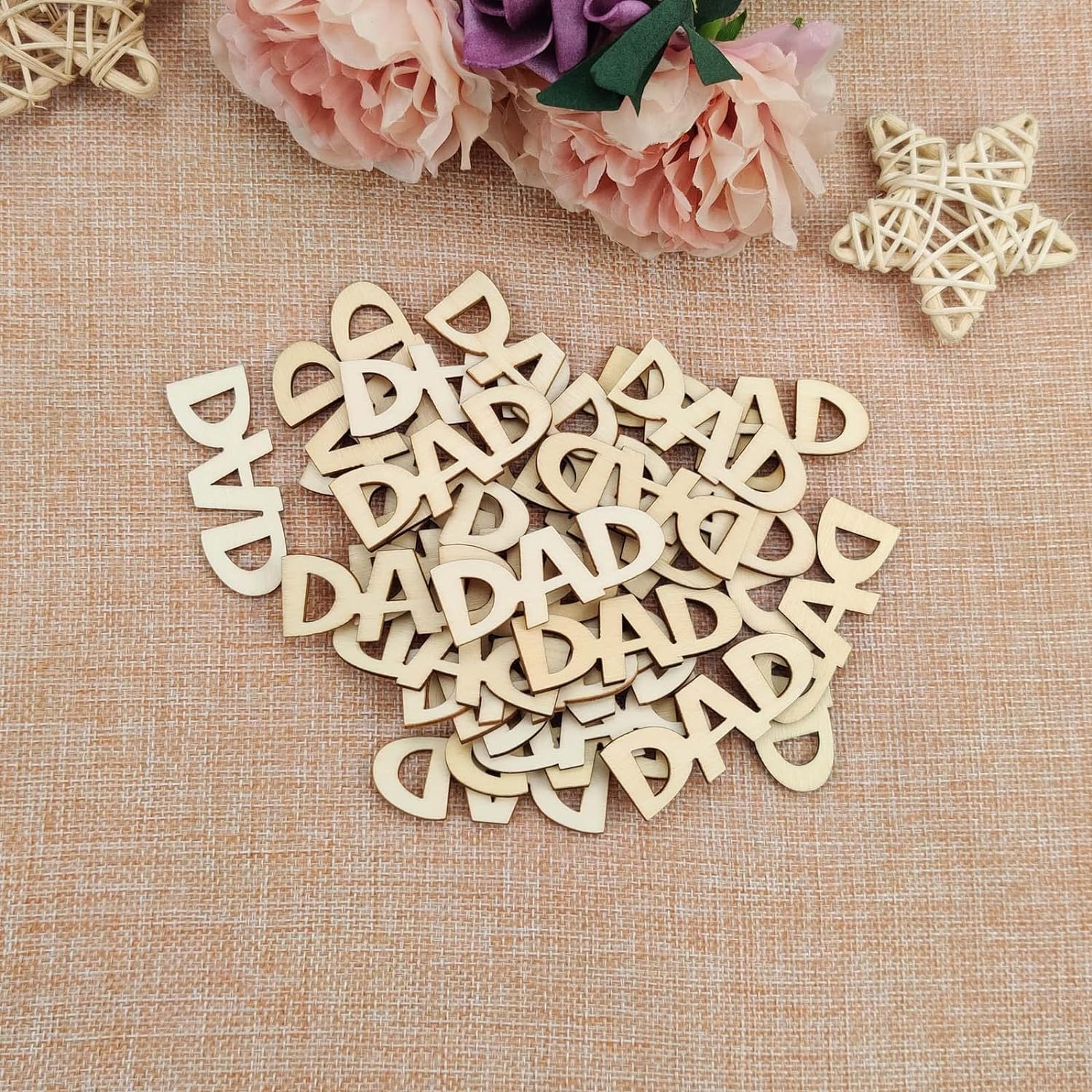 Wooden letters spelling 'DAD' on a textured fabric background with flowers.