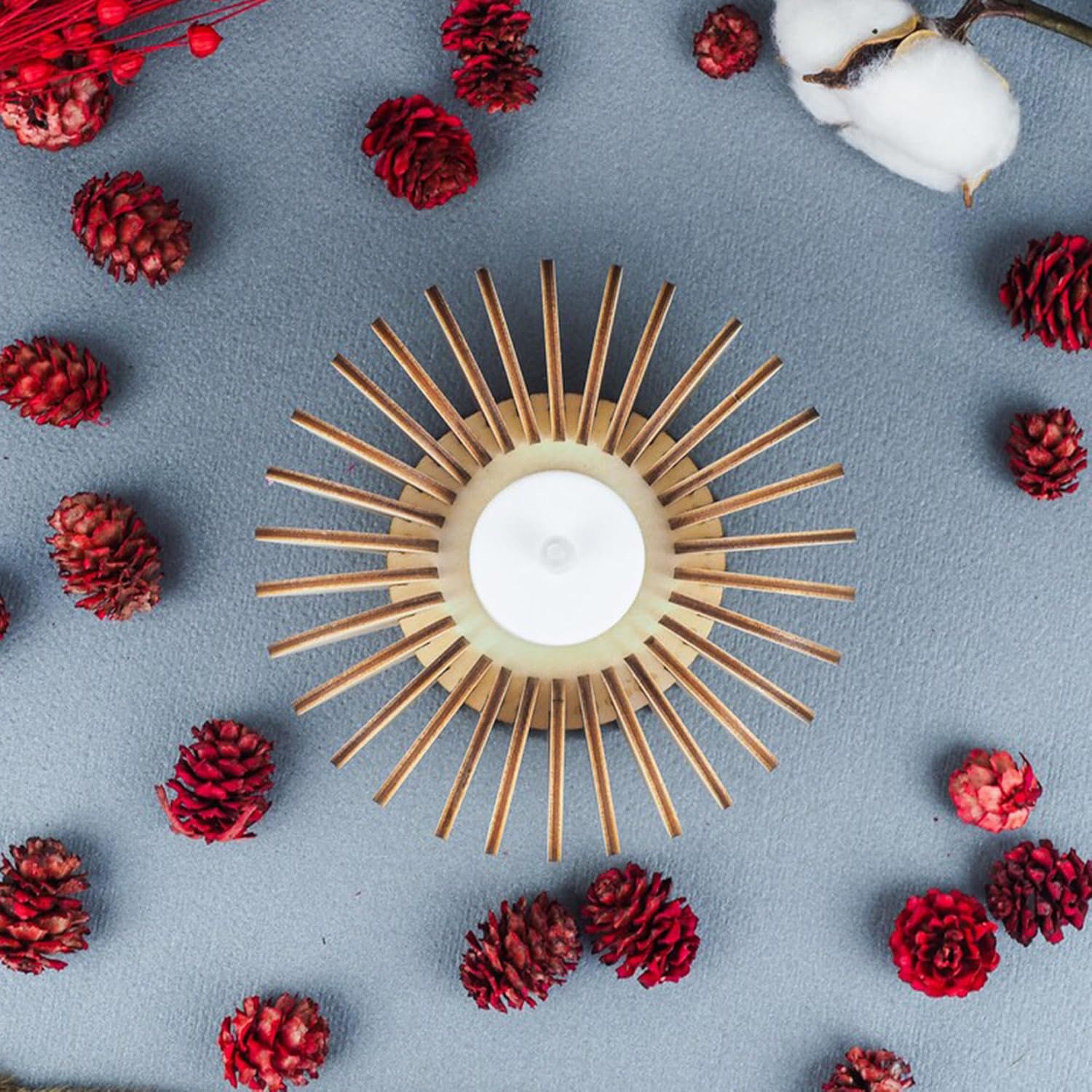 Decorative candle holder with red pinecones and white cotton on a gray background