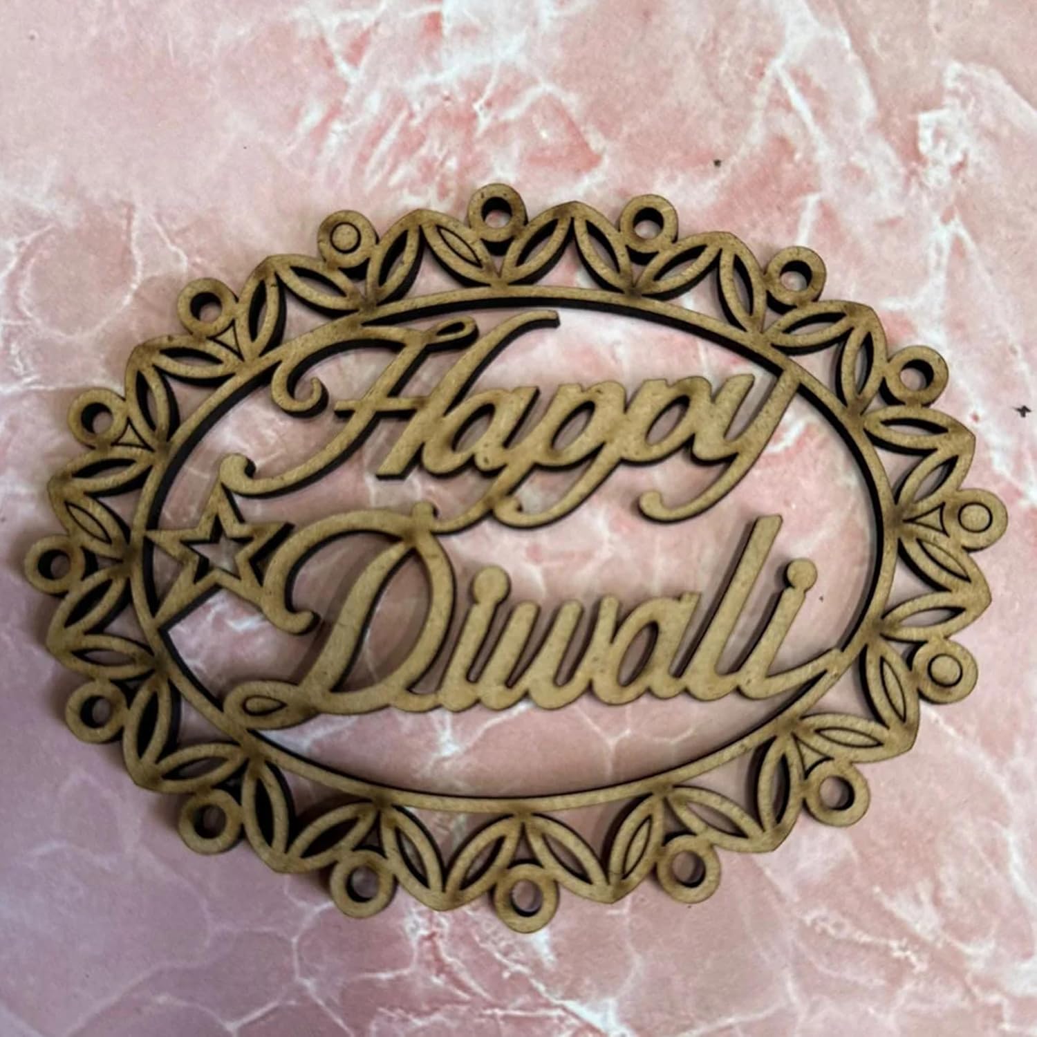 Decorative metal sign with 'Happy Diwali' text on a pink marble background