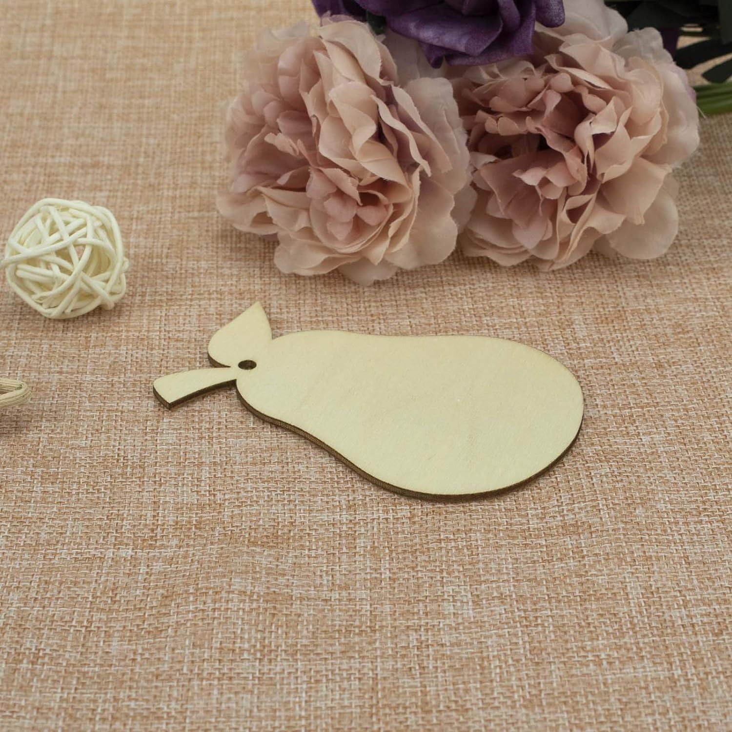 Gold leaflet on a textured beige surface with flowers in the background