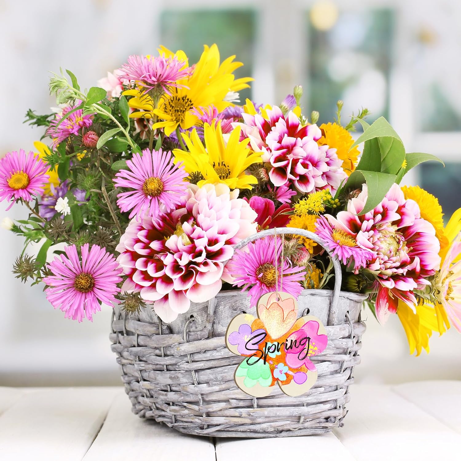 Basket of colorful flowers with a 'Spring' tag on a blurred background