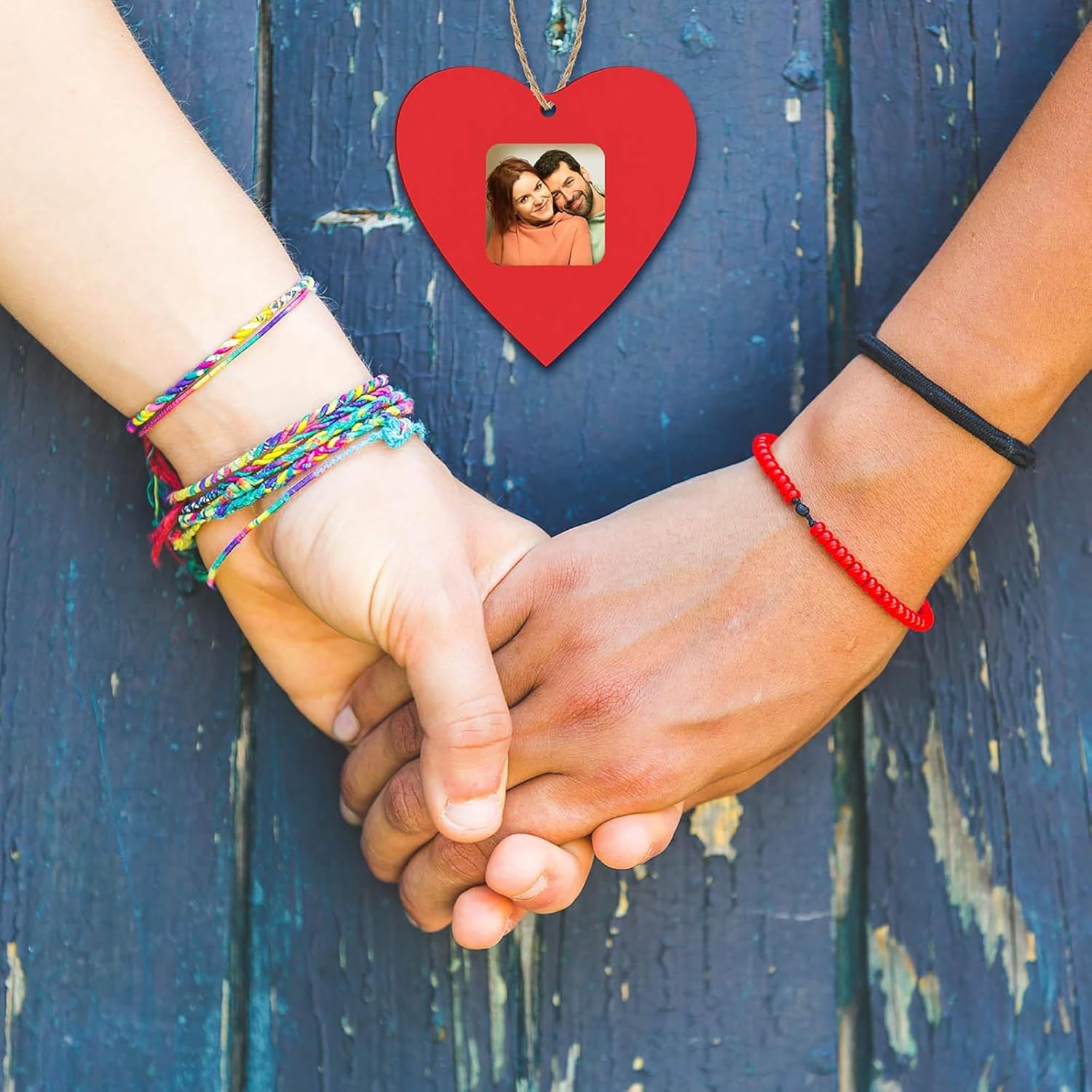 Two pairs of hands holding each other with a heart-shaped photo frame in the background.