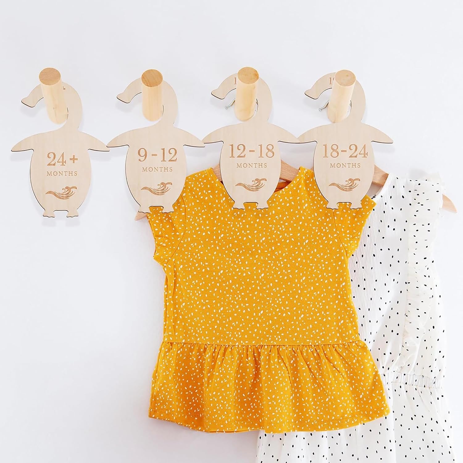 Yellow polka dot dress on wooden hangers with size labels against a white background