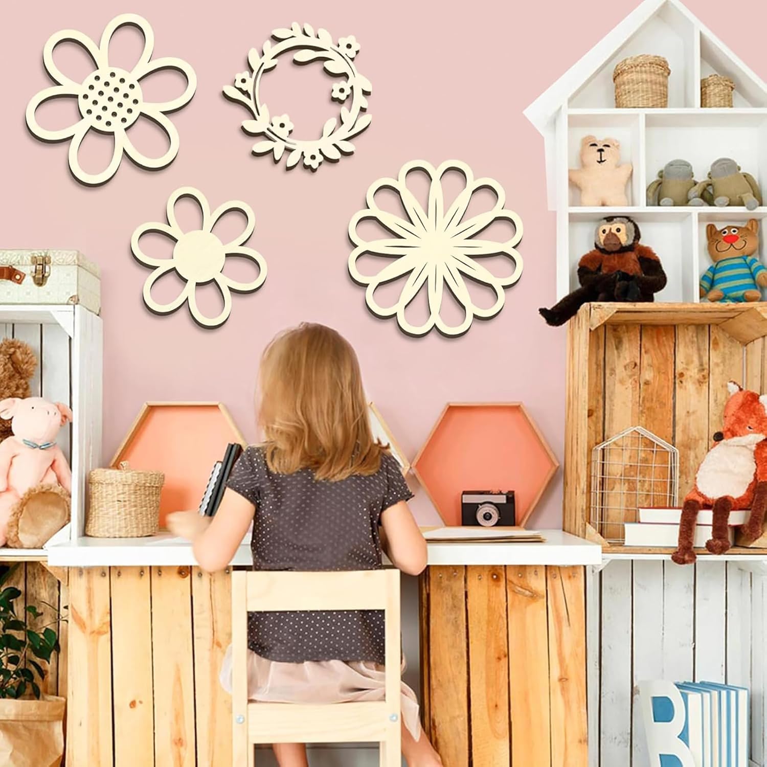 Child sitting at a desk in a playroom with decorative wall art and toys.