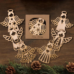Wooden angel decorations on a wooden surface with a 'Merry Christmas' card.