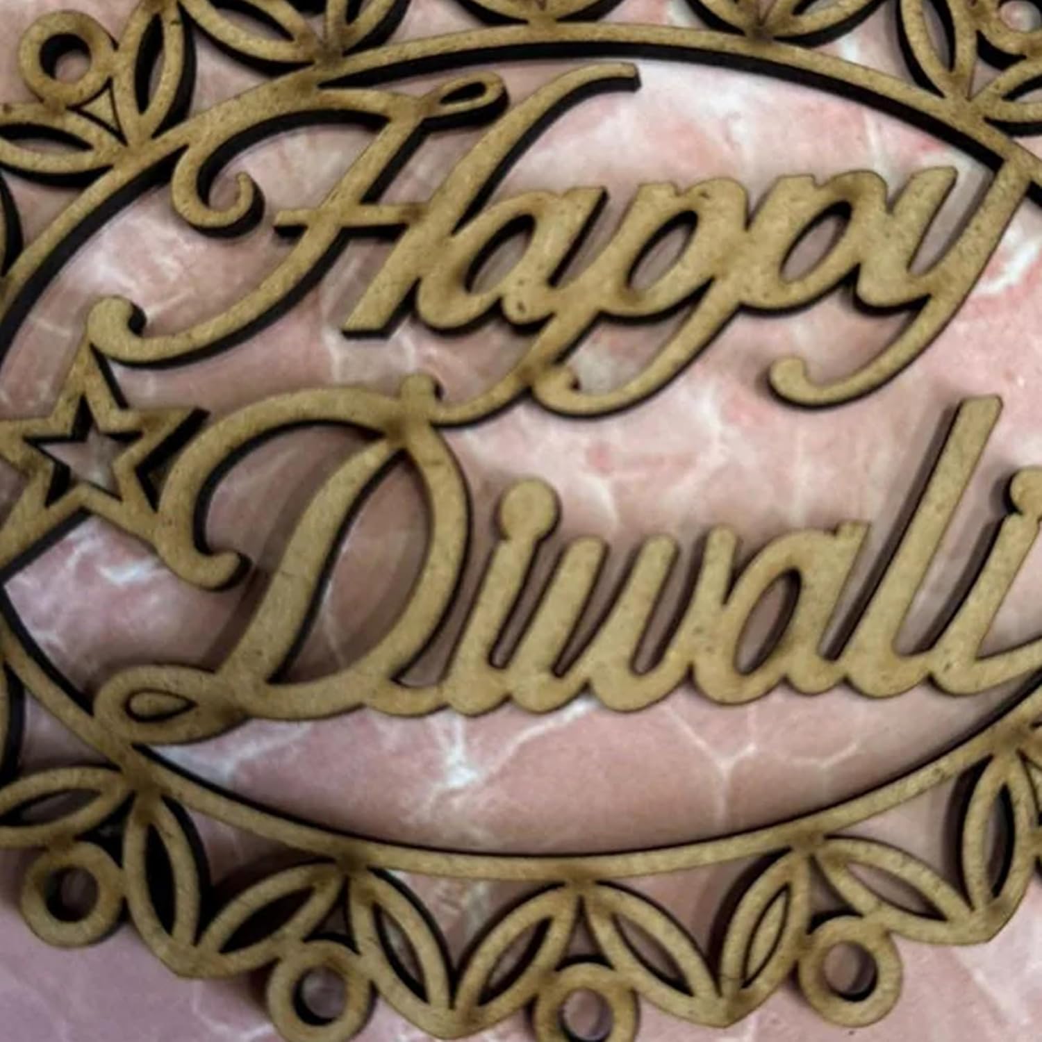 Decorative cutout with 'Happy Diwali' text on a pink marble background