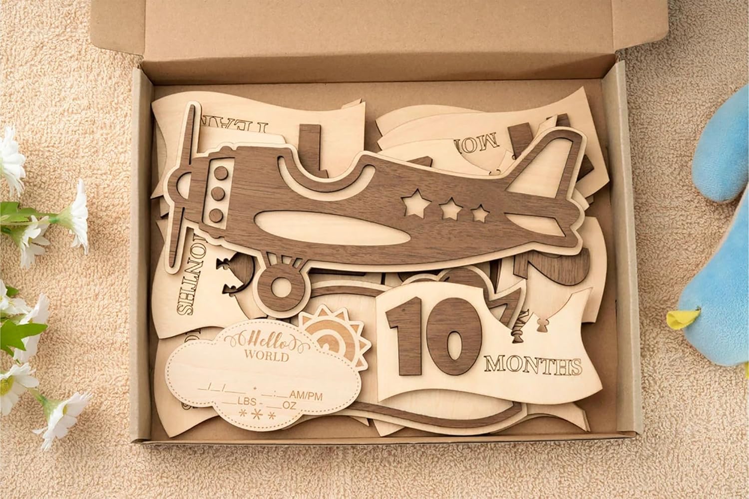 Wooden baby milestone cutout set with airplane design in a box on a beige surface.