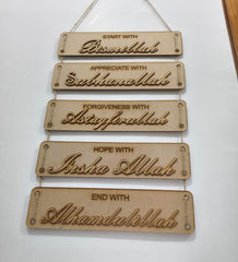 Wooden wall hanging with engraved phrases on a white background