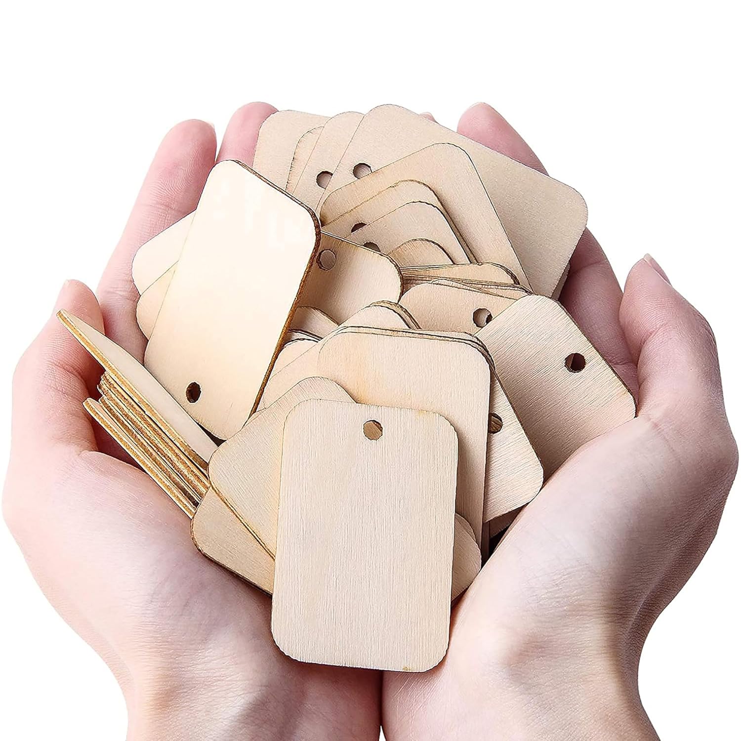 Hands holding a stack of small wooden tags with holes on a white background