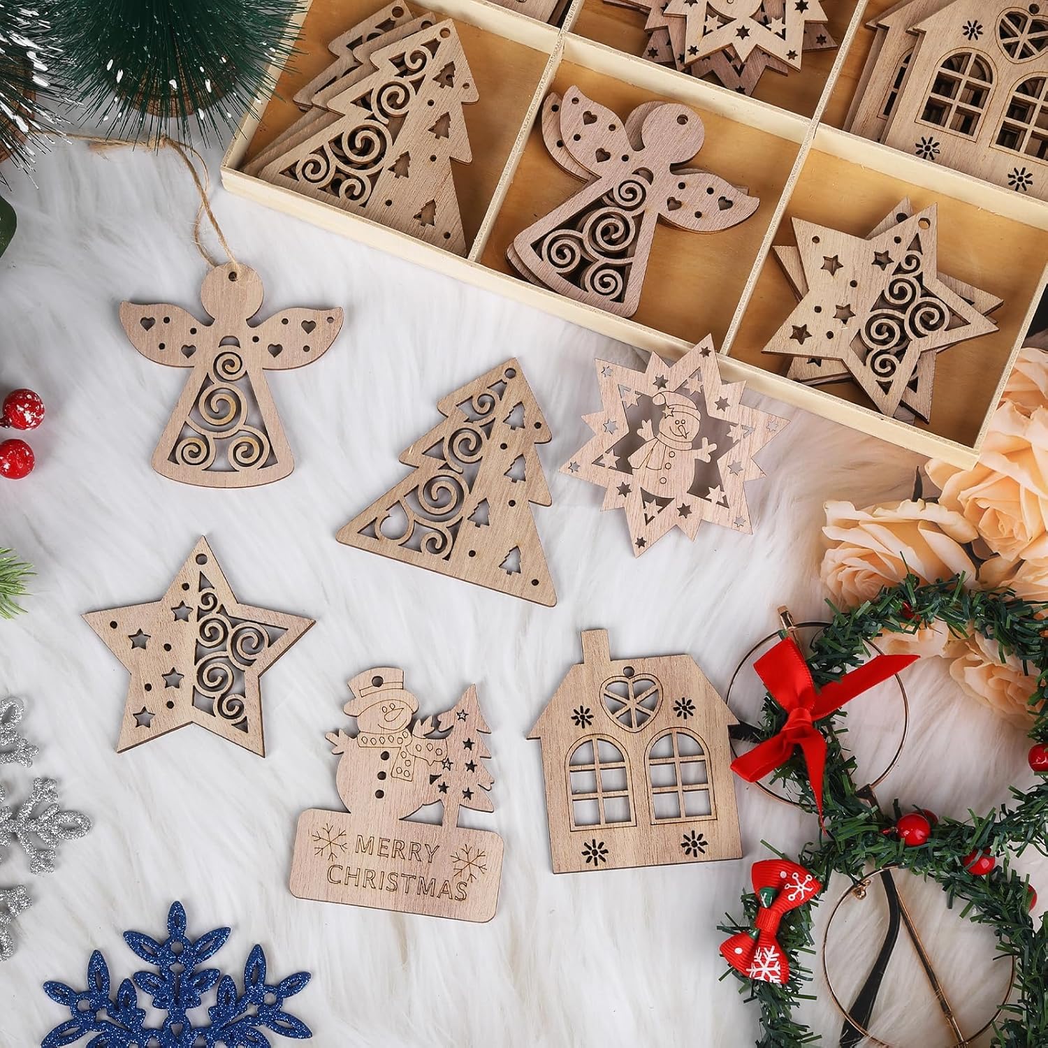 Wooden Christmas ornaments including stars, angels, and houses on a white surface with a wreath.