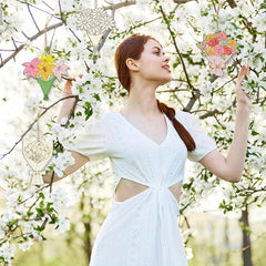 Woman in a white dress standing among white flowers with decorative floral elements.