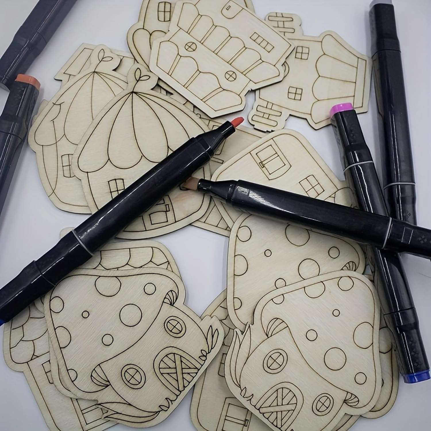 Wooden cutouts of cartoonish houses with markers on a white background