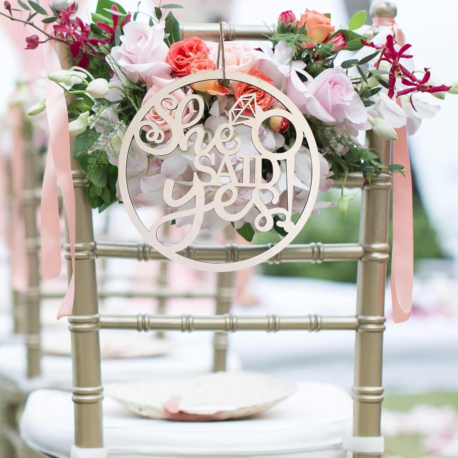 Chair with floral decorations and 'She said yes' sign at a wedding.