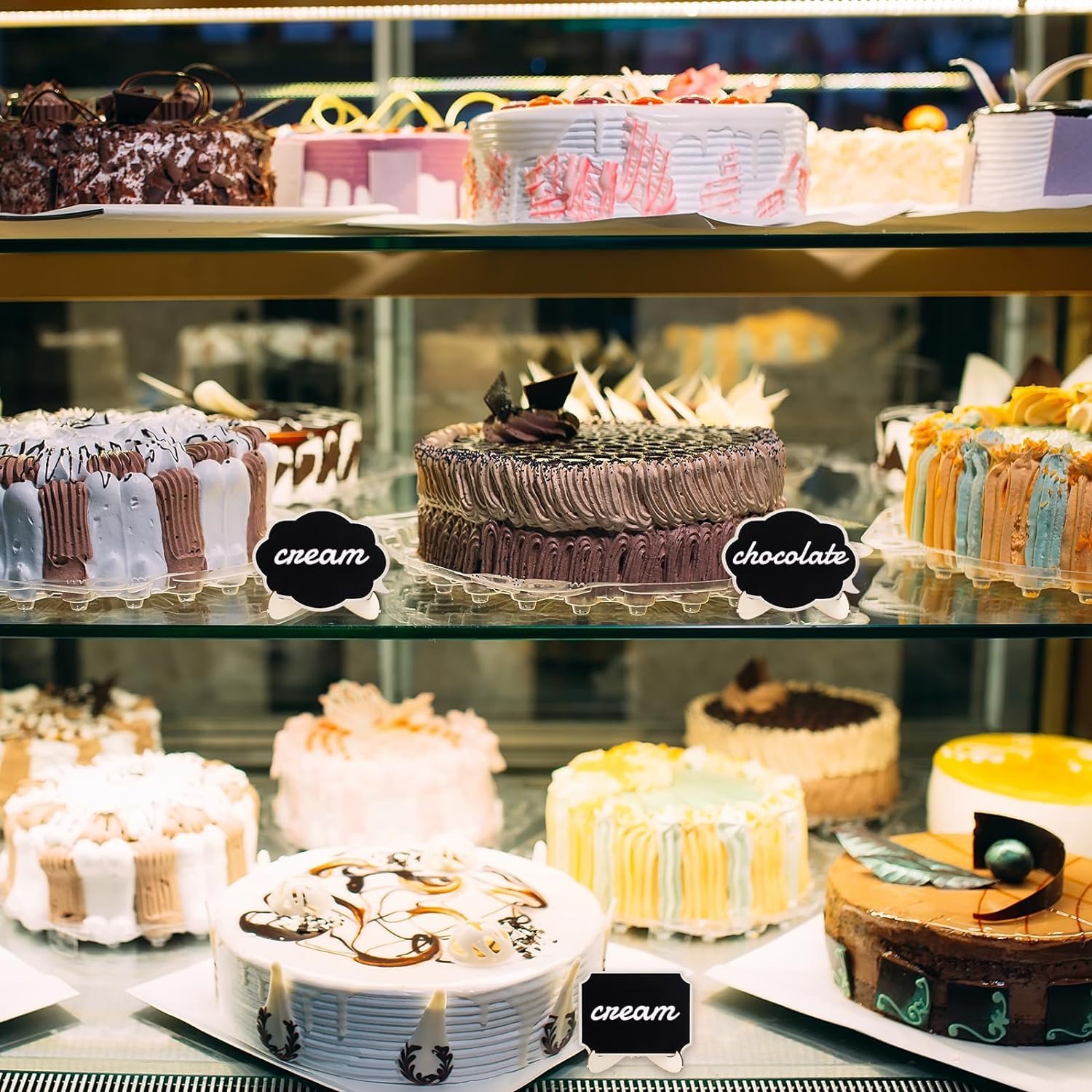Display of various cakes on a glass shelf with labels indicating flavors.