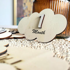 Wooden cloud-shaped item with '1 Month' text on a blurred background