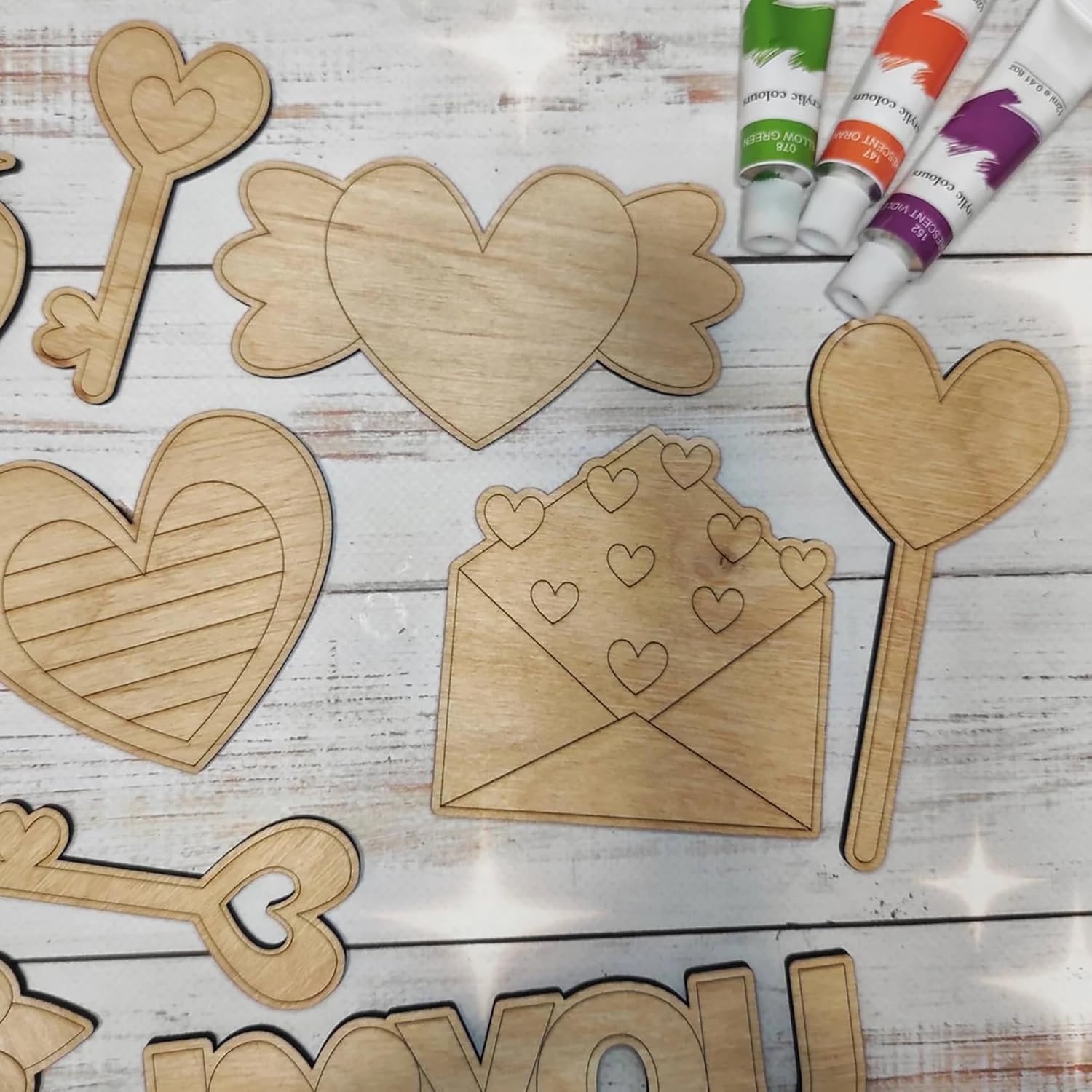 Wooden heart-shaped cutouts and paint tubes on a wooden surface