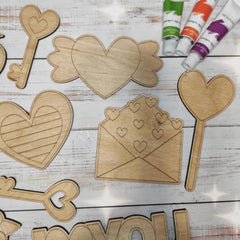 Wooden heart-shaped cutouts and paint tubes on a wooden surface