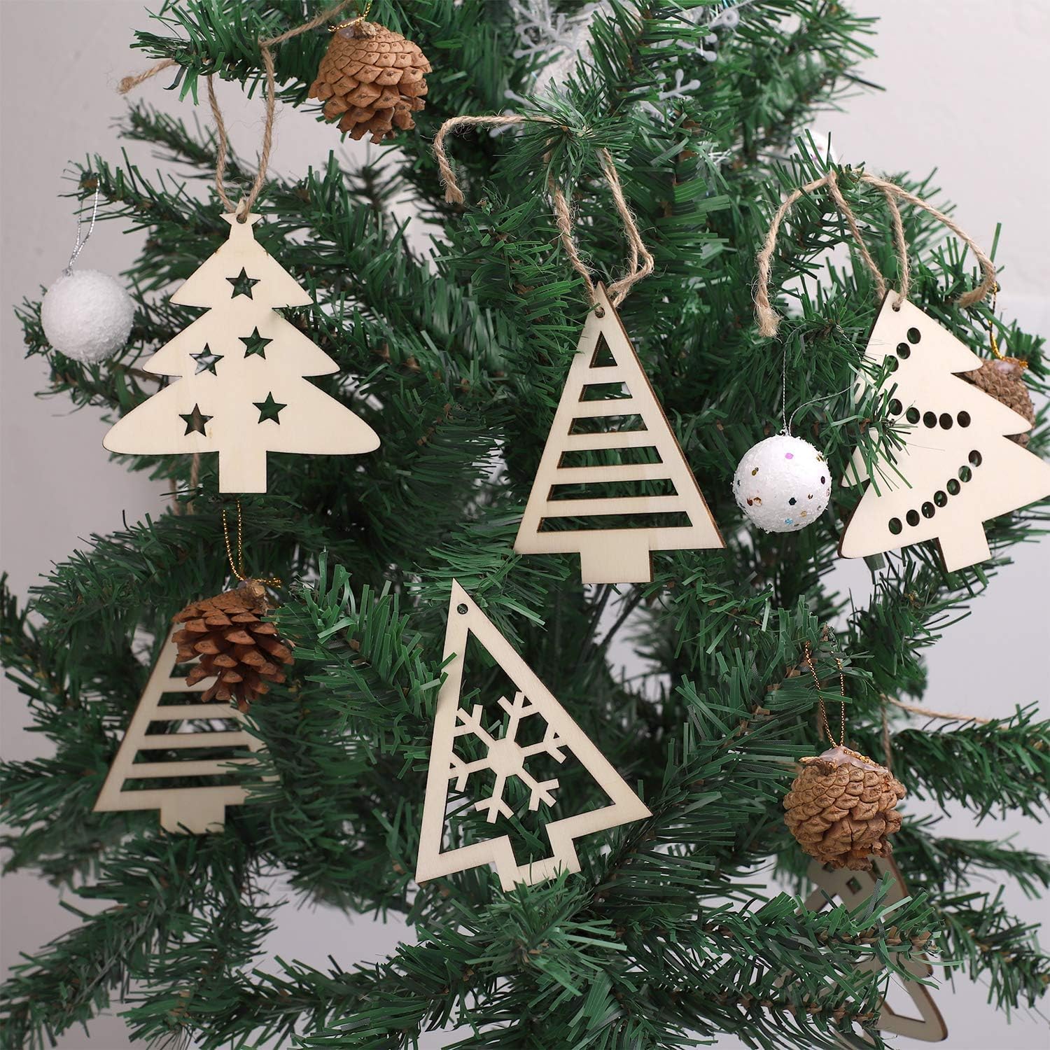 Wooden Christmas tree ornaments on a decorated tree with pine cones and white balls.