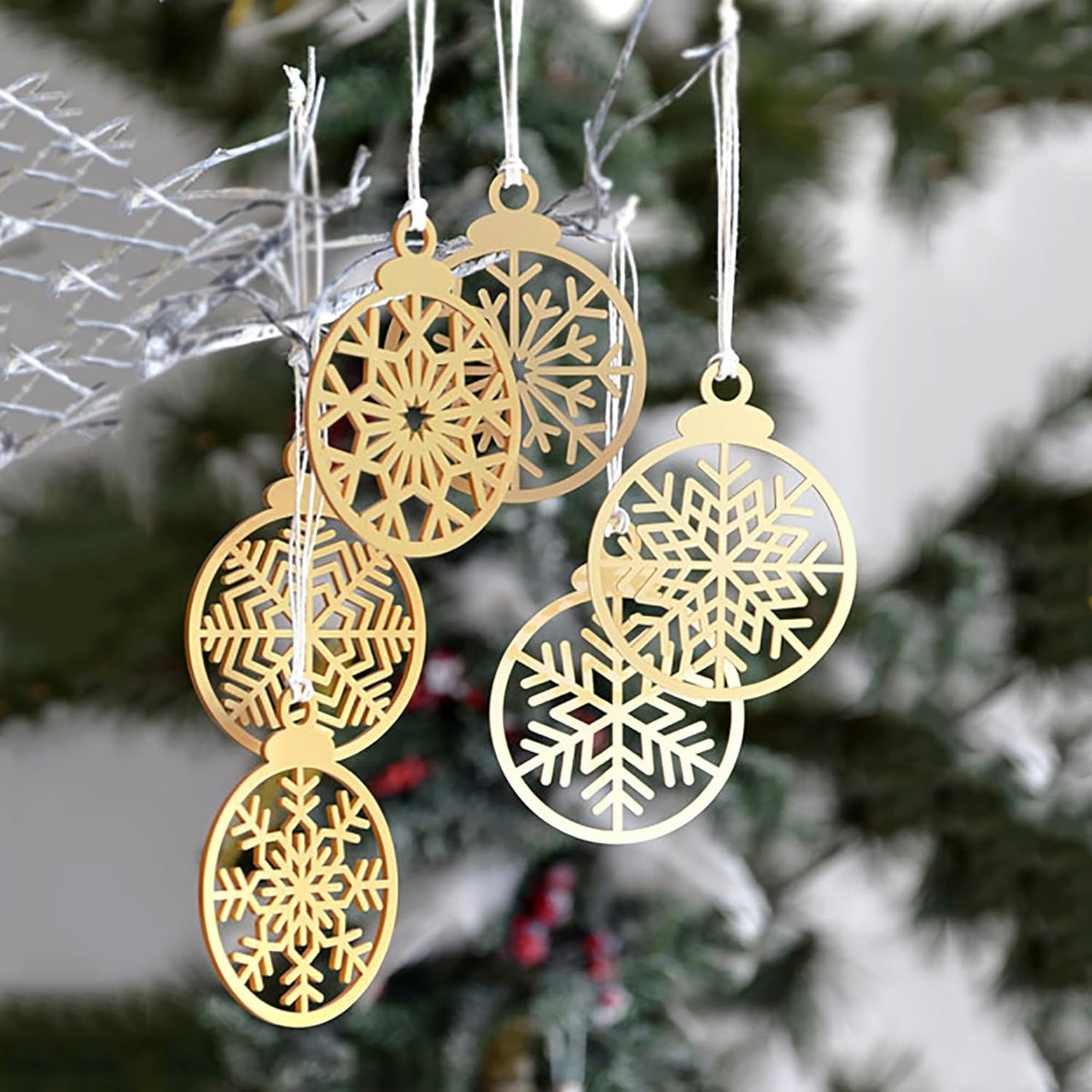 Gold snowflake Christmas ornaments hanging against a blurred Christmas tree background