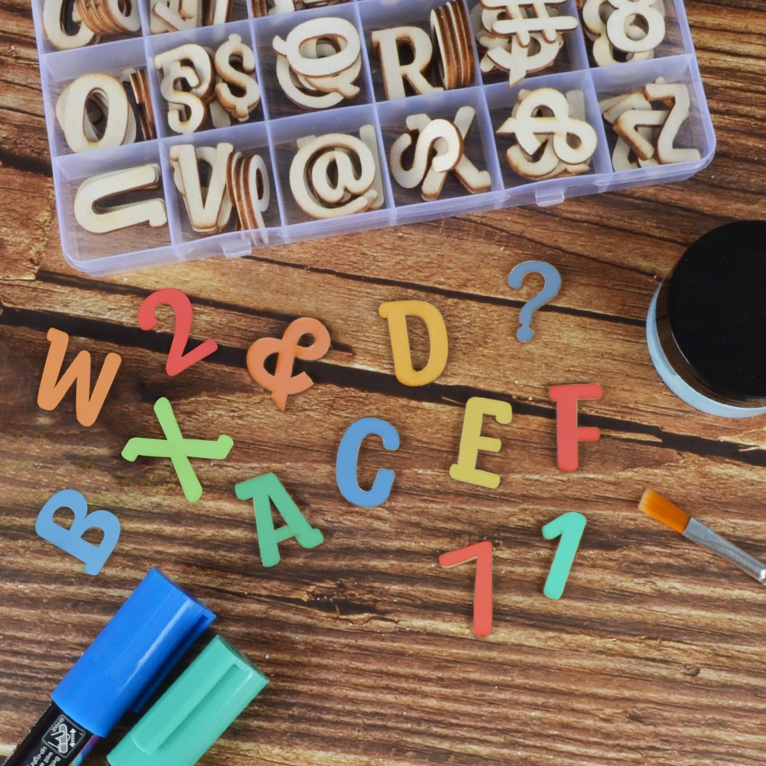 Colorful letter magnets on a wooden surface with a clear plastic container of letters.