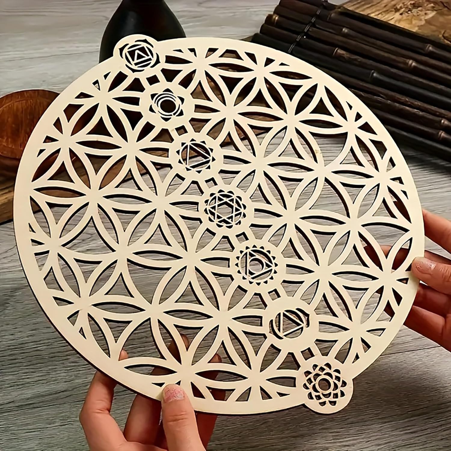 Geometric wooden cutout with intricate patterns held by hands on a wooden surface