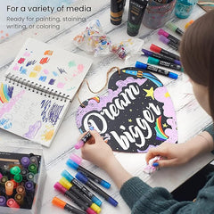 Person working on a craft project with markers and art supplies on a table.