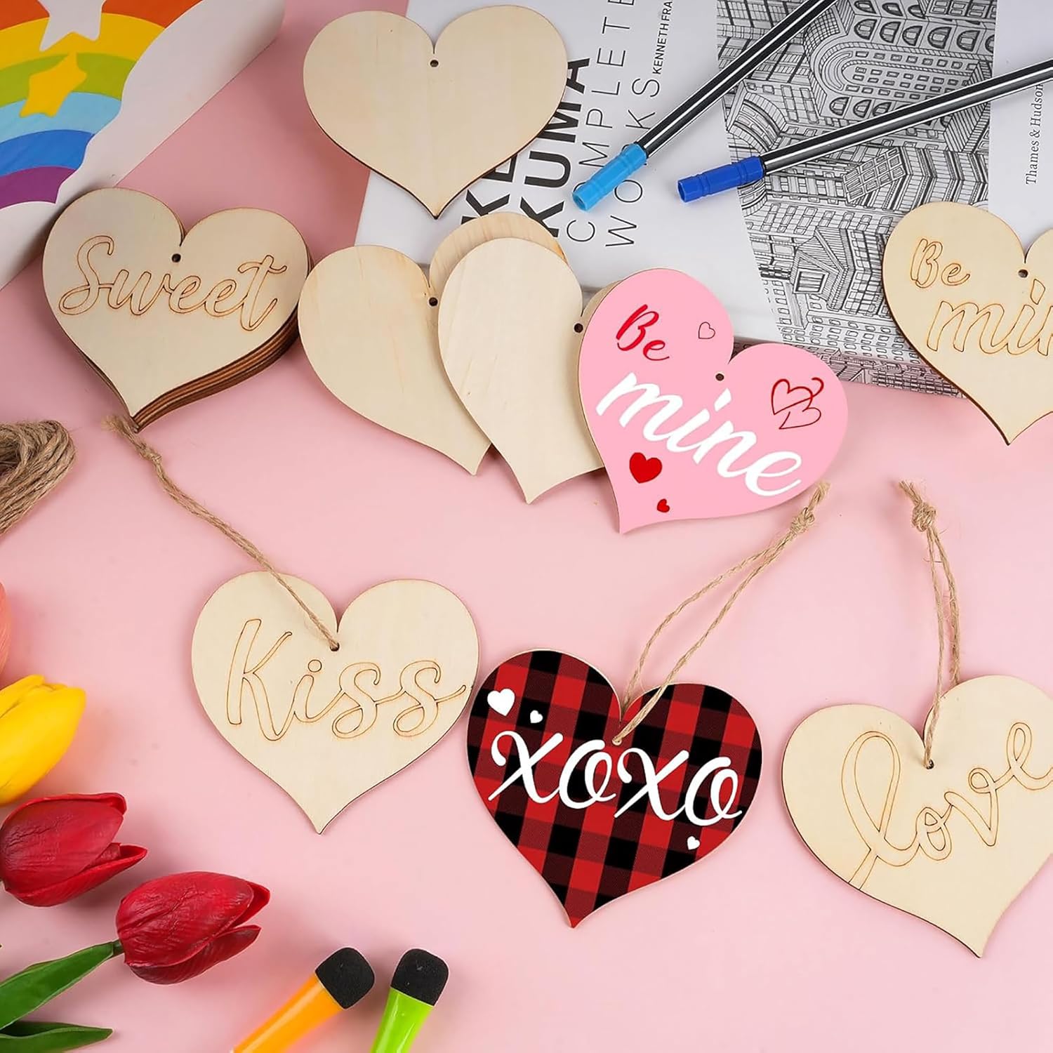 Heart-shaped wooden tags with various inscriptions on a pink surface with tulips and markers.