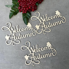 Wooden 'Welcome Autumn' decorations with berries and leaves on a gray background