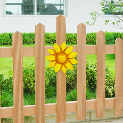 Wooden picket fence with a decorative sunflower in front of greenery