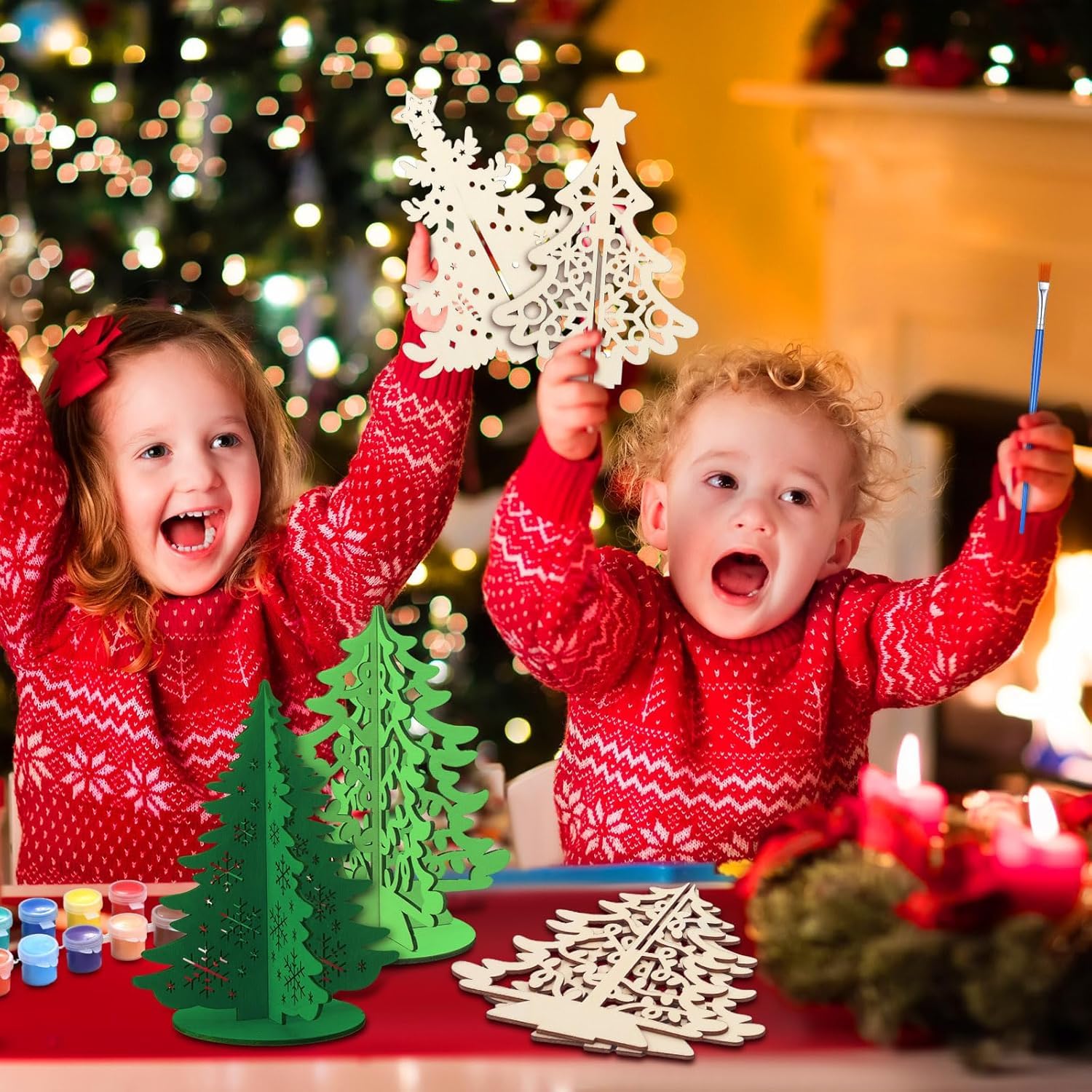 Two children in red sweaters playing with Christmas tree decorations in front of a decorated Christmas tree.