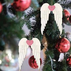 Decorative angel wings with pink hearts hanging on a Christmas tree with red ornaments.