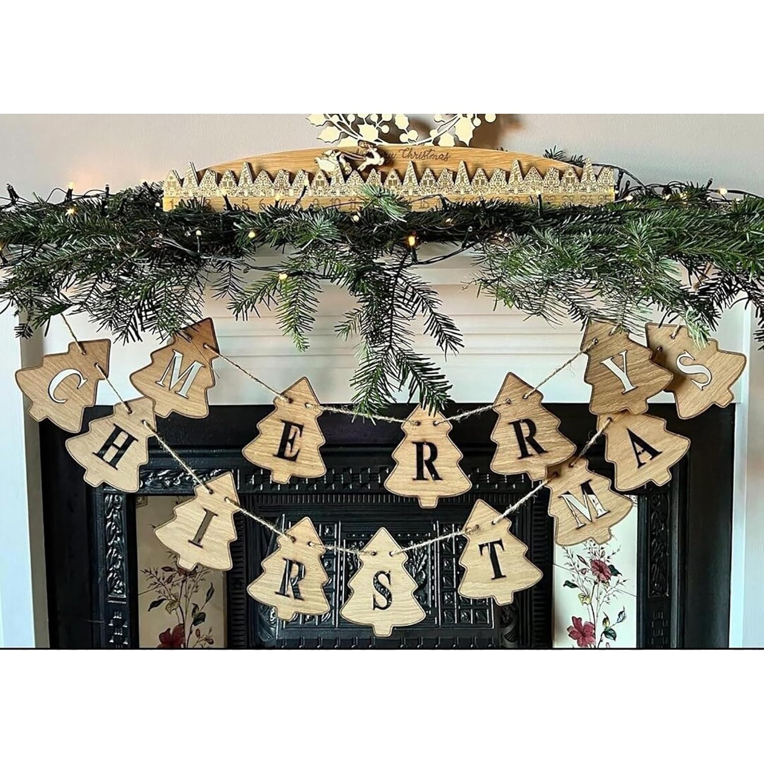 Wooden 'Merry Christmas' banner hanging on a decorated fireplace mantel.