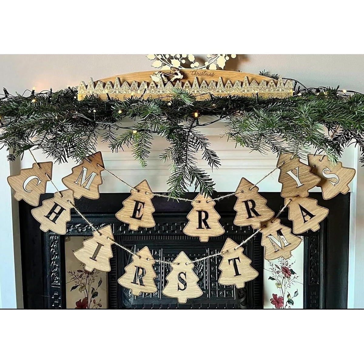 Wooden 'Merry Christmas' banner hanging on a decorated fireplace mantel.