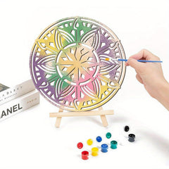 Colorful mandala art on a stand with paint supplies and books in the background