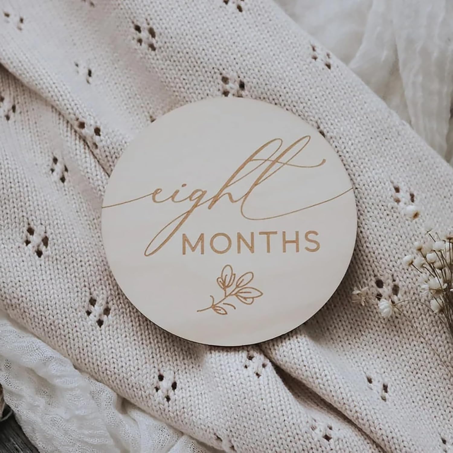 Round wooden plaque with 'eight months' text on a textured fabric background