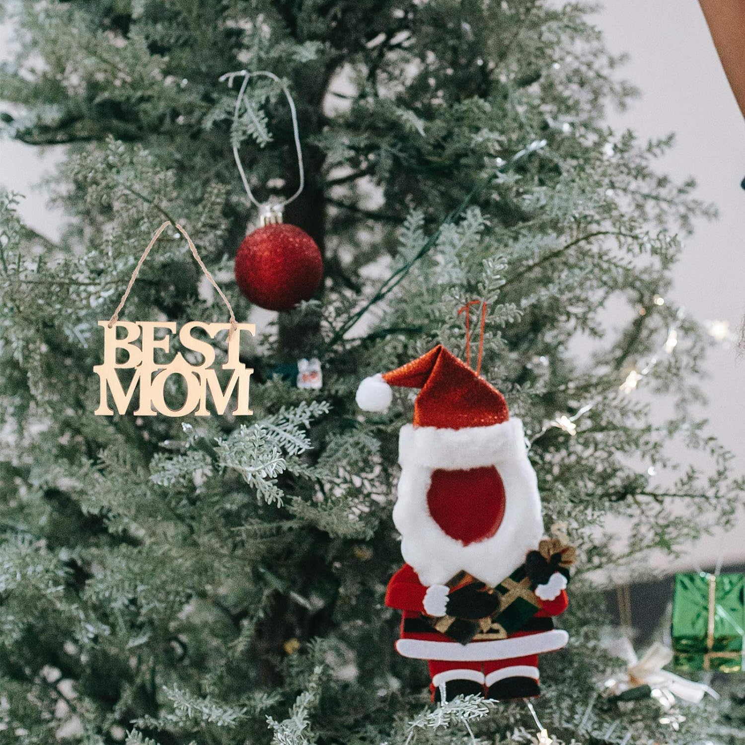 Decorative ornaments on a Christmas tree, including 'BEST MOM' and a Santa Claus figure.