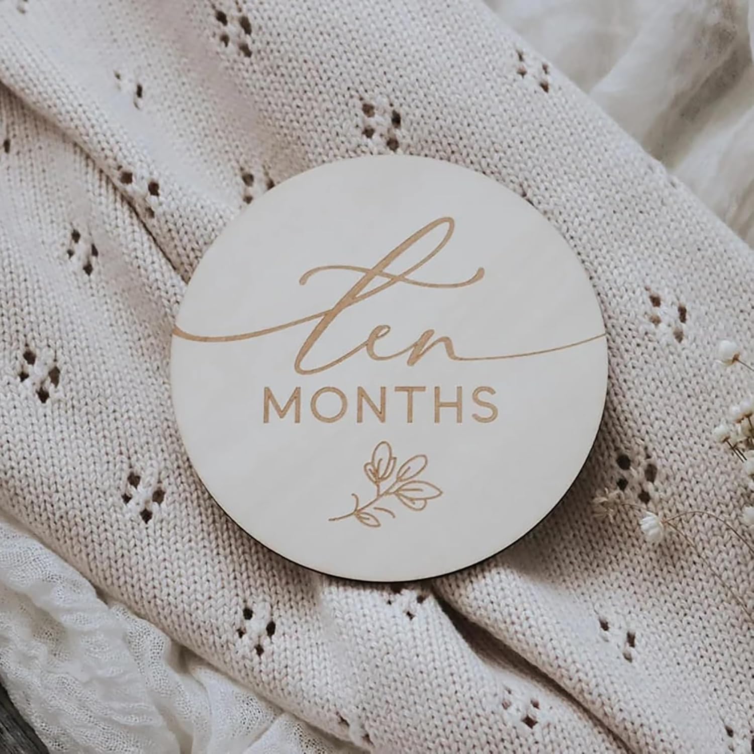 Round wooden coaster with 'ten months' text on a textured fabric background