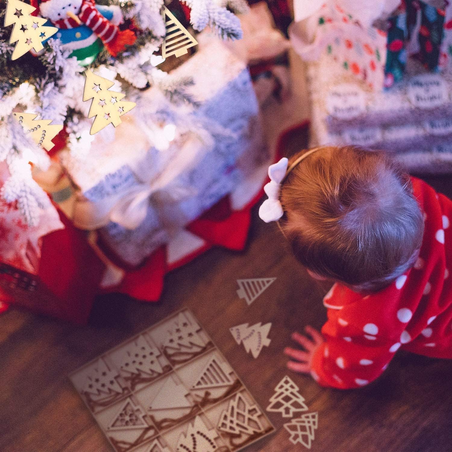 Child playing with wooden Christmas tree decorations near a decorated Christmas tree.