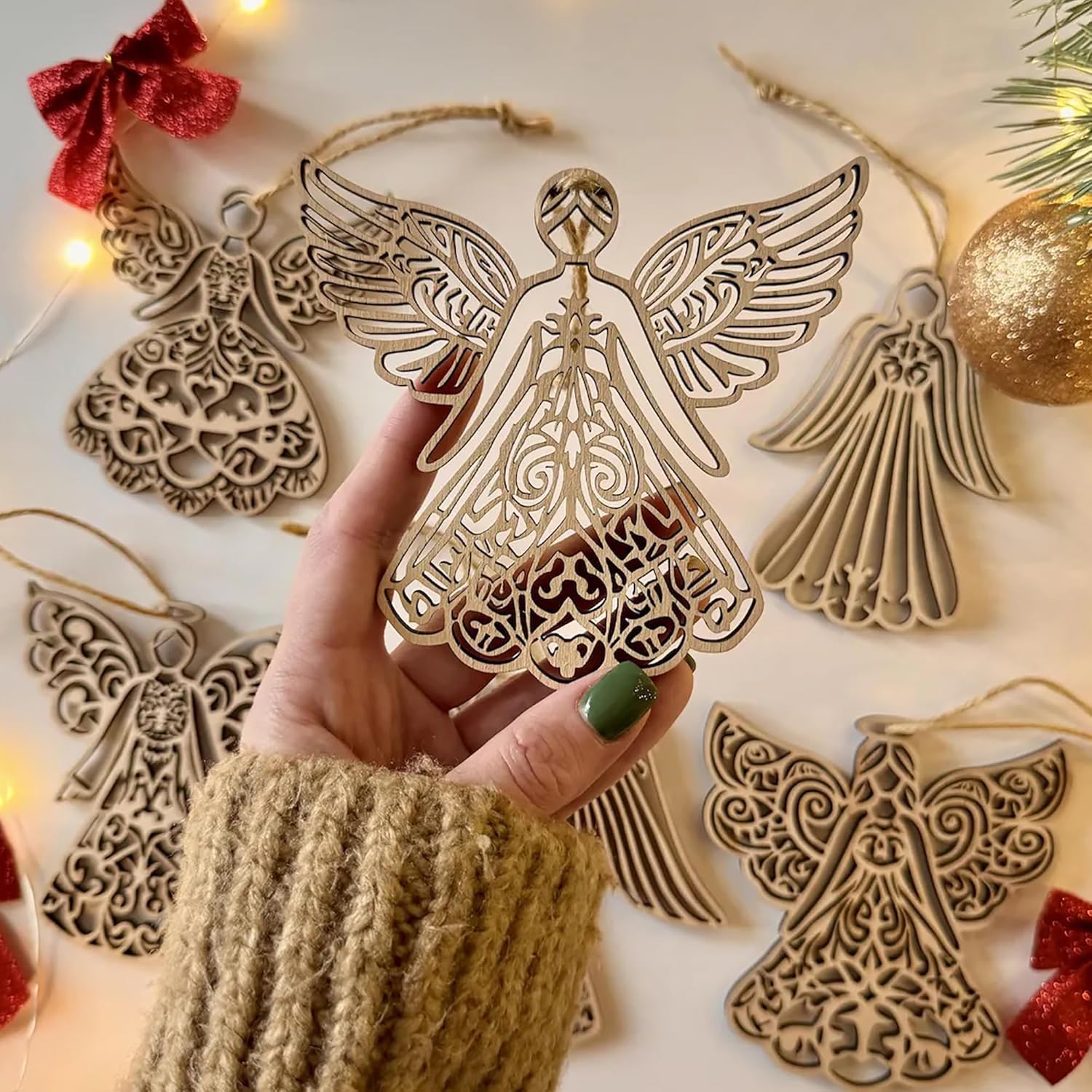 Decorative angel ornaments with a hand holding one, surrounded by more angel ornaments and Christmas decorations.
