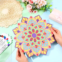 Colorful mandala art being held by a hand on a light blue surface with floral decorations.
