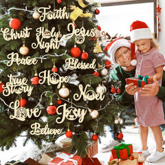 Two children in front of a Christmas tree with decorative words and ornaments.