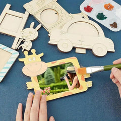 Wooden picture frames with animal designs on a blue surface, with a hand painting one of them.