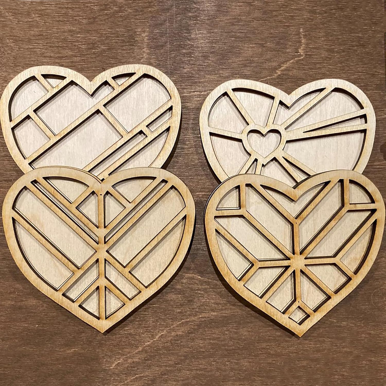 Four wooden heart-shaped cutouts with geometric patterns on a wooden surface