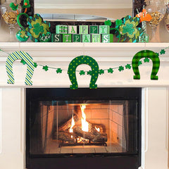 Decorated fireplace mantel with St. Patrick's Day decorations including shamrocks, horseshoes, and 'Happy St. Pat's' sign.