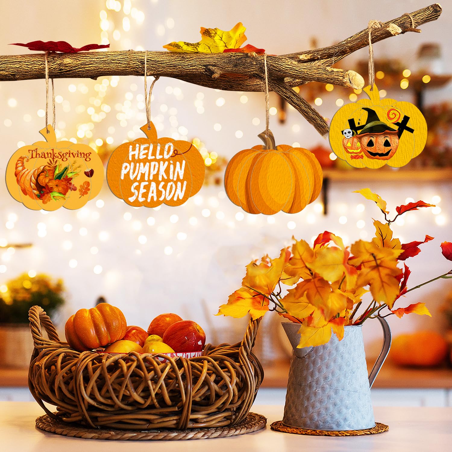 Decorative setup with pumpkins, leaves, and autumn-themed signs on a branch against a blurred indoor background.