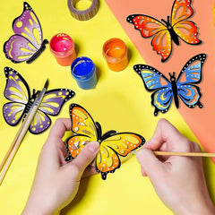 Butterfly-shaped craft items with paint and brushes on a colorful background