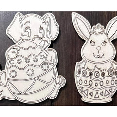 Two black and white bunny and egg designs on a wooden background