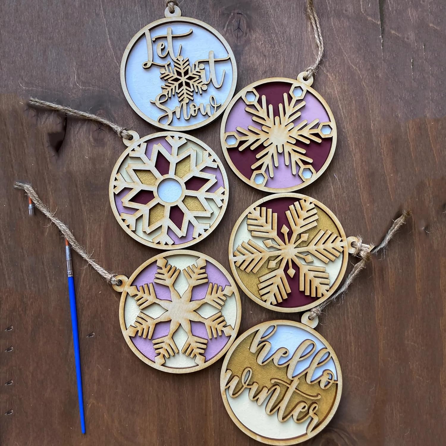Decorative wooden ornaments with snowflakes and text on a wooden background