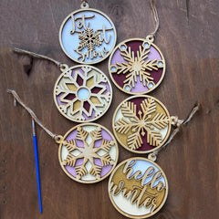 Decorative wooden ornaments with snowflakes and text on a wooden background